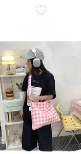 Detail of pink gingham canvas tote bag showing high-capacity design and wide strap in a cafe