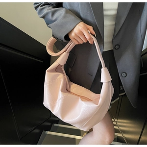 Detail of pink soft leather tote bag showing pleated texture and knotted strap design