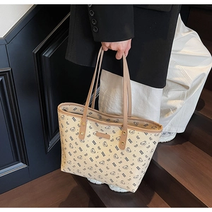 Dettaglio ravvicinato di motivi a orsetto e fiocco su una grande borsa tote color crema
