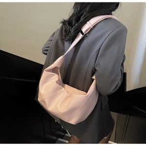Detailed view of pink pleated leather tote bag with knotted strap on model's shoulder