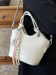 Borsa a secchiello bianca minimalista con manici annodati e ciondolo da tennis