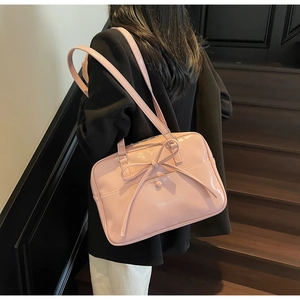 Pink glossy leather tote with large bow knot shown in a stylish staircase scene