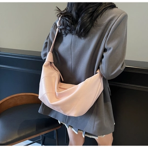Detail of light pink hobo bag with knotted strap on model in grey oversized blazer
