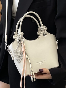 Elegante borsa a secchiello beige con manico a nodo e ciondolo a forma di racchetta
