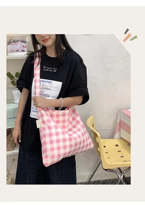 Detail view of pink plaid canvas tote bag with wide strap and branded side label