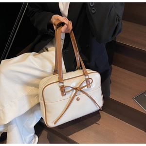 Detail of vintage oil wax leather bag featuring a bow accent and contrasting brown edges