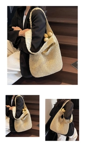 Detail view of a large beige straw tote bag showing fine weave texture and summer style