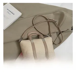 Close-up of woven beige handbag with brown leather handles and silver hardware