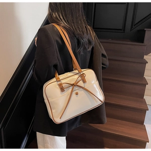 Detail of a minimalist bow tote bag with brown straps on a white glossy leather finish