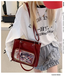 Detail of red oil-wax leather ita bag with large clear PVC window and adjustable straps