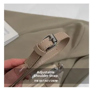 Detail of adjustable leather shoulder strap with silver buckle on beige square bag