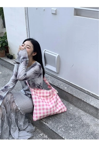 Close-up of pink and white checkered canvas tote bag in a casual outdoor setting