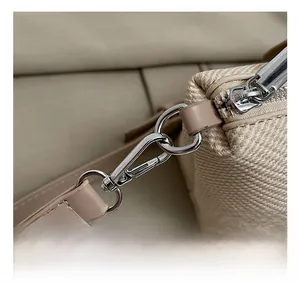 Detailed macro view of high-quality silver metal hooks and beige canvas texture on bag