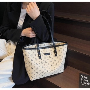 Dettaglio della borsa tote in tela beige con motivi di orsi e manici in pelle nera