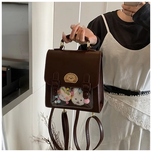 Detail view of the transparent PVC window with plush charms on a brown leather ita bag