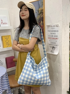 Blue and white gingham tote bag on shoulder showing large capacity and soft fabric texture