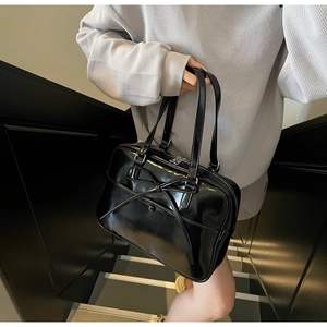 Detailed view of black patent leather tote bag with ballet bow accent and silver zipper