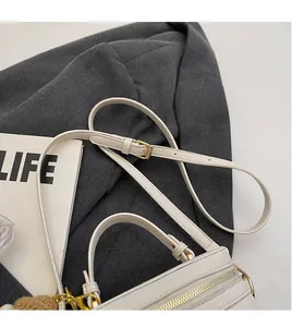 Detail view of smooth leather box bag with adjustable long strap and bear charm