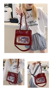 Detail of red oil wax leather ita bag featuring a large transparent PVC window for pins