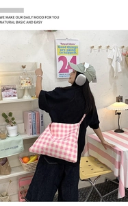 Detailed side view of pink and white gingham tote bag worn by model in a cozy study room