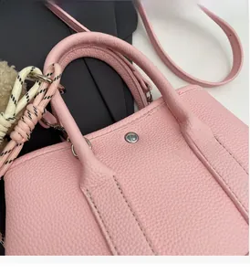 Détail d'un sac seau rose en cuir grainé avec pendentif en corde tressée et boucle argentée