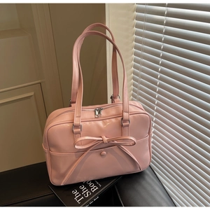 Close-up of pink glossy tote bag featuring a large bow detail and elegant handles