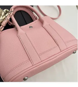 Gros plan du sac à main en cuir grainé rose avec doubles poignées et rivets en argent