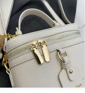 Detail of smooth gold metal zippers and lychee grain leather on the beige handbag