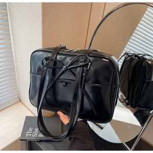 Detailed view of black patent leather tote bag with bow detail and glossy finish