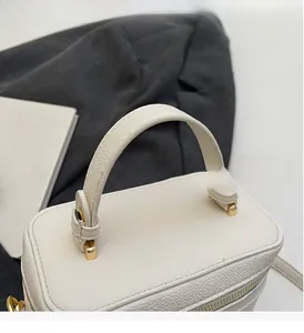 Detail view of white lychee pattern box bag with reinforced handle and gold hardware