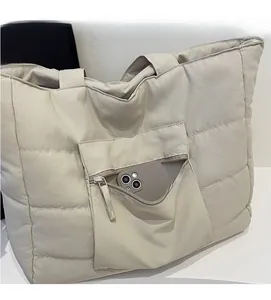 Détail d'un grand sac fourre-tout matelassé beige avec une poche zippée pour téléphone