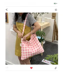Detail of a large pink and white plaid tote bag with wide shoulder straps for daily commute
