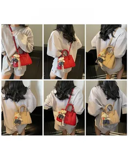 Détail du sac seau en cuir avec poignées et breloque ours en peluche pour un look chic