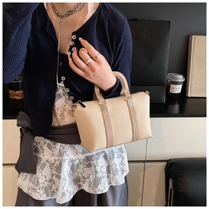 Chic beige woven Boston bag with silver hardware worn by a model in a lifestyle setting