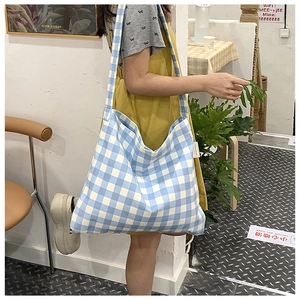 Detail of blue and white checkered canvas tote bag with side woven brand label