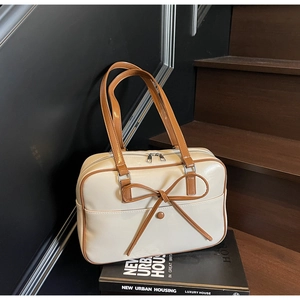 Detail of cream white tote bag with brown bow accent and leather texture on wooden steps