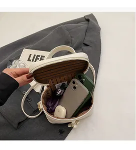 Detail view of white pebbled leather box bag showing interior capacity and striped lining