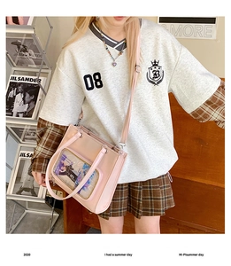 Pink crossbody bag with clear display window shown in a stylish lifestyle setting