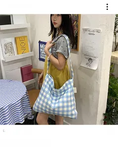 Detail view of large light blue gingham canvas tote bag worn by a model on shoulder