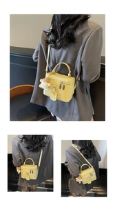 Detail view of yellow box handbag with teddy charm and adjustable crossbody strap