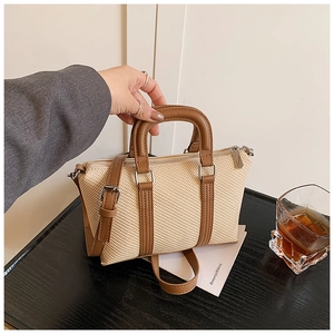 Detail of a beige woven contrast handbag with brown leather handles and silver hardware