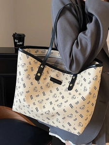 Borsa tote crema con stampa orso e manici neri indossata da una modella fiera