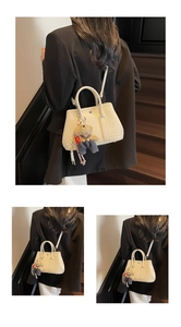 Détail du sac seau blanc avec motif litchi et breloque ours en peluche sur la bandoulière