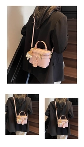 Pink lychee grain box bag with top handle and cute plush charm on dark wooden stairs