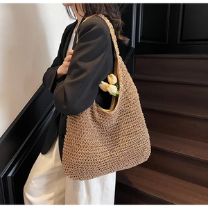 Detail of a large woven straw hobo bag showing thick texture and a wide shoulder strap
