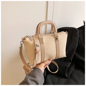 Detailed texture of beige woven handbag with brown faux leather straps and silver hardware