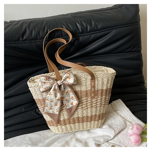 Detail of striped woven tote bag with brown leather handle and floral silk scarf charm