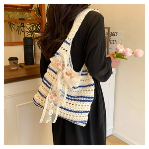 Detail of woven tote bag with blue stripes, lace bow, and delicate floral embroidery