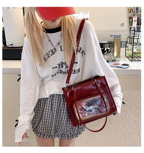 Detail view of burgundy faux leather ita bag featuring a large clear PVC display window
