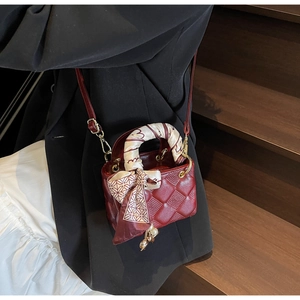 Macro shot of a red quilted leather bag with a printed silk scarf and a heart charm
